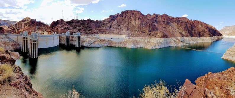 Hoover Dam - brown wooden dock on river near brown mountain under blue sky during daytime