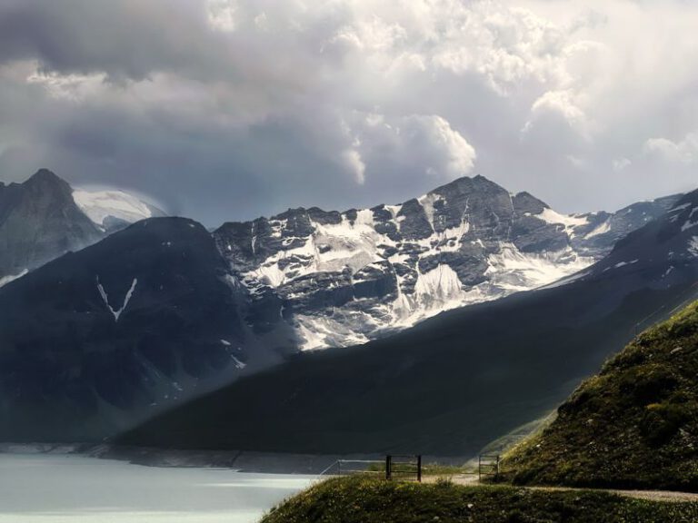 Grande Dixence - a scenic view of a mountain range with a lake in the foreground