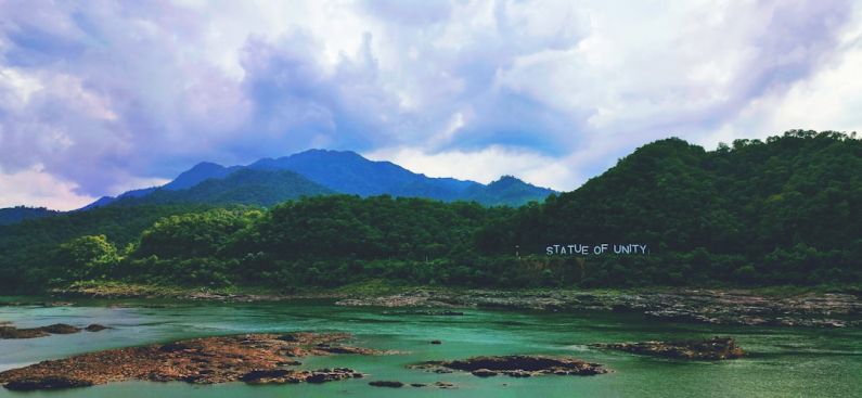 Statue Of Unity - green mountain beside body of water under cloudy sky during daytime