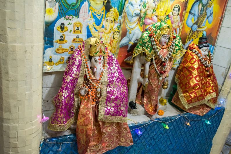 Place Festivals - a group of statues of hindu deities in front of a painting