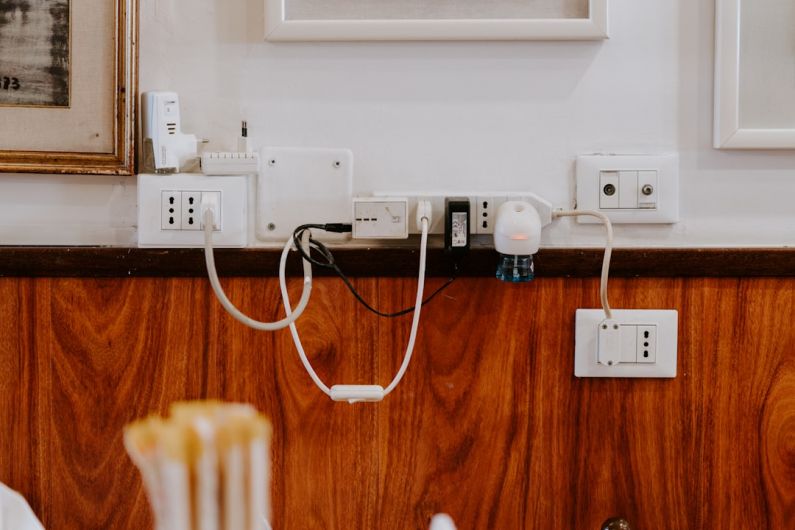 Undersea Cables - white power strip on brown wooden floor