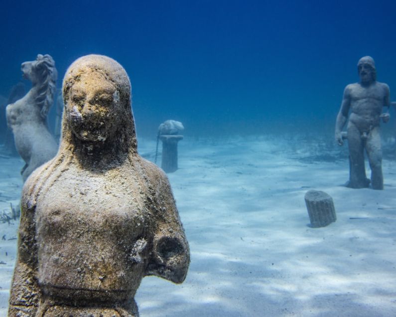 Underwater City - a statue of a man and a woman in the water