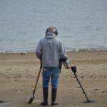 Sunken Treasure - a man with crutches and a cane standing on a beach