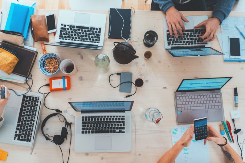 Digital Divide - people sitting down near table with assorted laptop computers