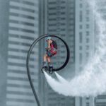 Jetpack - Man in Red Jacket Riding Bicycle on White Water Wave